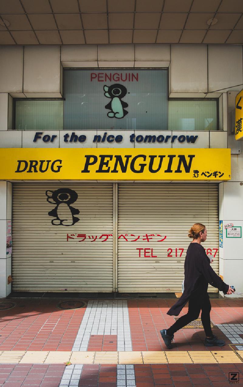 Someone walking in front of a closed store of DRUG PENGUIN