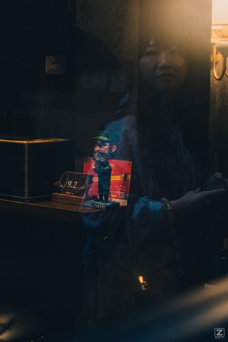 A woman reflection on a window with a Fidel Castro figurine behind