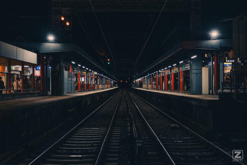 A train station taken from the side, in the middle of the rails