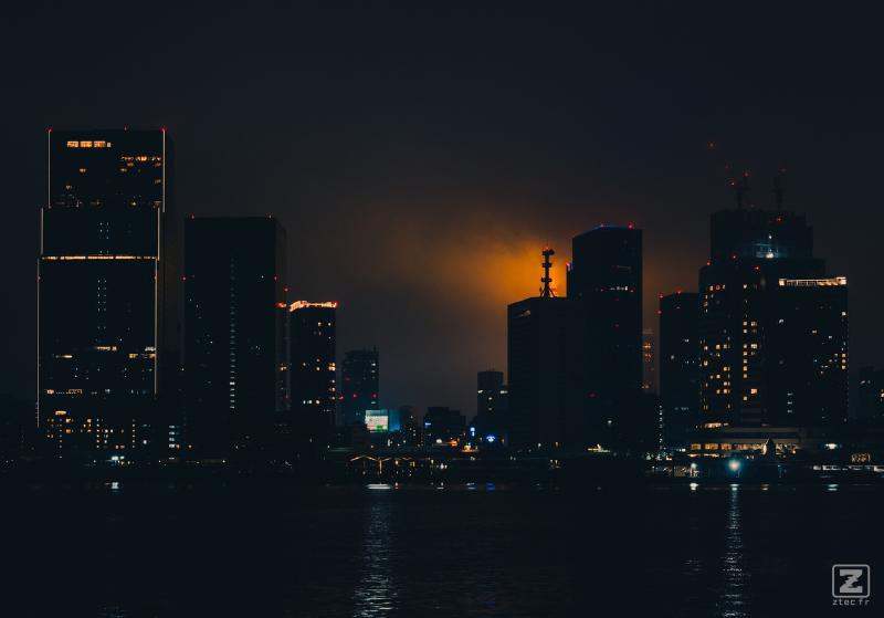Tokyo bay at night with an orange glow coming from the Tokyo tower from behind skyscrapers  
