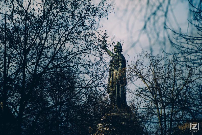 The République statue behind trees.