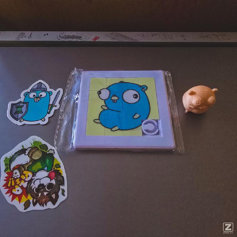 Swag from the Golang room. A sticker, a Puzzle, and a 3d printed figurine. All of a Golang Gopher. 