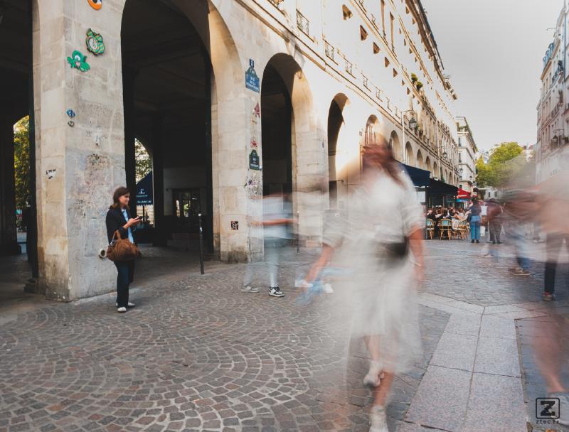 A person waiting surrounded by faded people. 