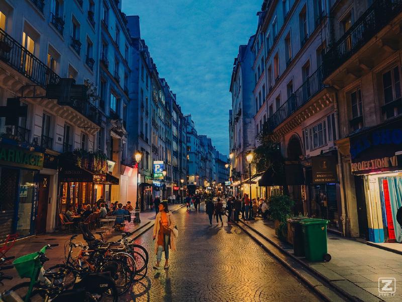street of Paris at early night with streets and shops light bouncing of the pavement. Some People are walking on the streets, some are in bars and restaurants. 
https://www.flickr.com/photos/ztec/53213546684/