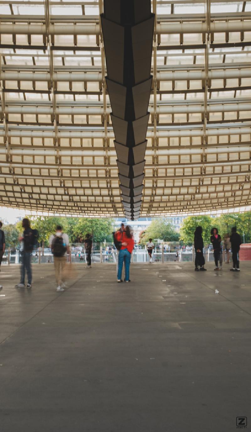 Two persons hugging under the Châtelet canopée. People around them are blurry. 