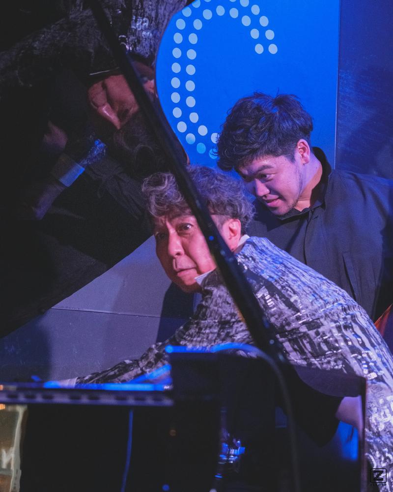 Makoto is all hands in the piano strings to fix microphone placement that interfered with the sound.