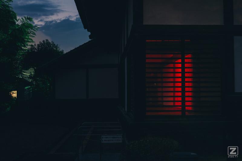 A house taken in the dark. A red glow come from the inside