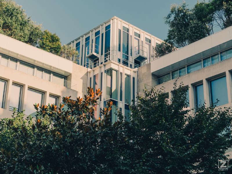 A square-ish building in Paris with lots of vegetation around and on it. 