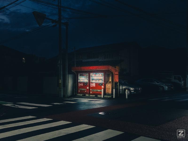 Two Coca Cola dispenser lighted in the middle of the street in the dark