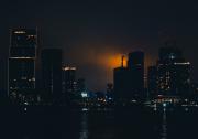 Tokyo bay at night with an orange glow coming from the Tokyo tower from behind skyscrapers  