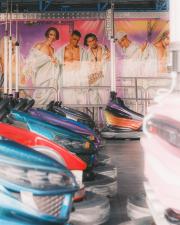 Bumpercars parked with a drawing on the wall of a generic boys-band.