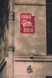 1968 - 2018 fight with a space invader. Mosaic mural. A punk, also in mosaic, is on the bottom.