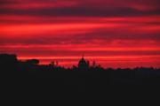 Red sky coloured by the sun rise of the morning, forming a silhouette from the roof buildings afar.