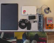 Desk with multiple electronic devices such as computer, batteries, and gameboy