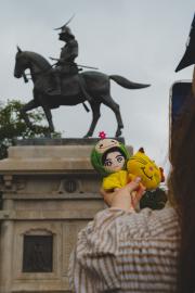 A tourist is taking picture of plushies in front of a monument. 