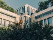 A square-ish building in Paris with lots of vegetation around and on it. 