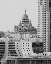 Sacré-coeur in the back (in the center of the frame), and tall modern building surrounding it in the "front" 