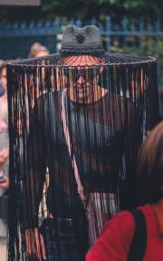 A person with a hat with long strings falling from the top to the feets