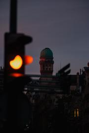 An orange traffic light, with observatory dome lighten up by the early morning sun.