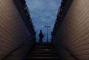 Stairs of a Paris metro/Subway station with the typical white tiles on walls.(both side).
    On top of the stairs, a person's silhouette is visible with a pole light in a paris typical shape. 
    The sky is blue-ish like way after the sun has set, but still lighting the sky.
    https://www.flickr.com/photos/ztec/53213529963/