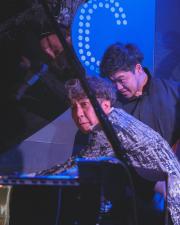 Makoto is all hands in the piano strings to fix microphone placement that interfered with the sound.