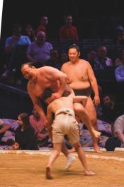A sumo in battle with a child, losing to the power of the child.