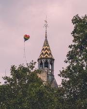 A heart shaped balloon raising in the sky in the front of a Parisian church