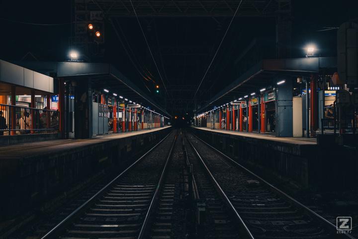 A train station taken from the side, in the middle of the rails