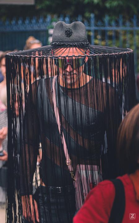 A person with a hat with long strings falling from the top to the feets