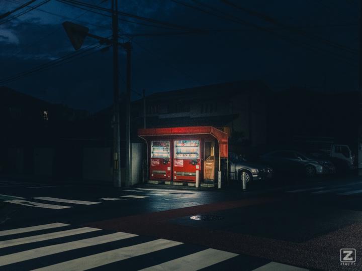 Two Coca Cola dispenser lighted in the middle of the street in the dark