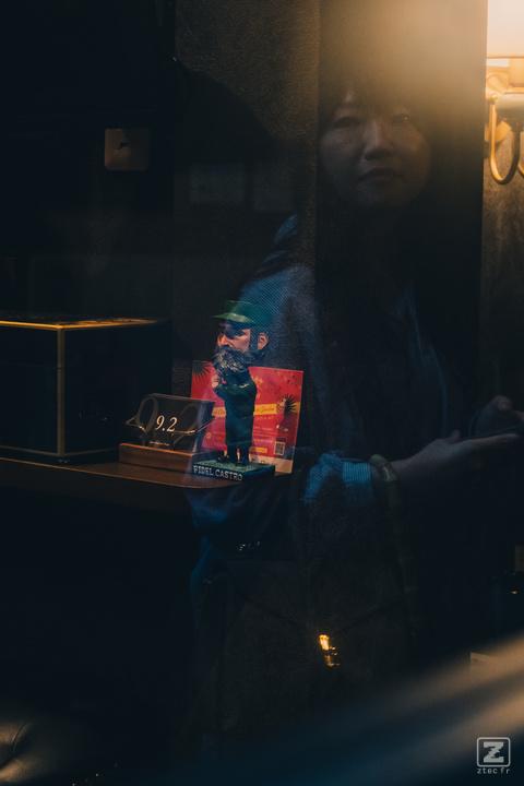 A woman reflection on a window with a Fidel Castro figurine behind