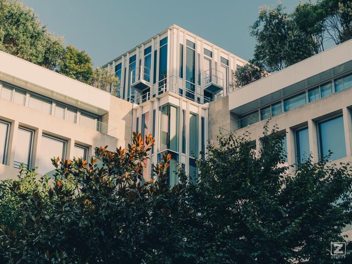 A square-ish building in Paris with lots of vegetation around and on it. 