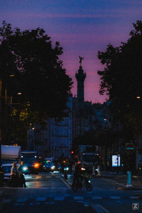 Paris street by early morning, with the Bastille tower piercing building far away