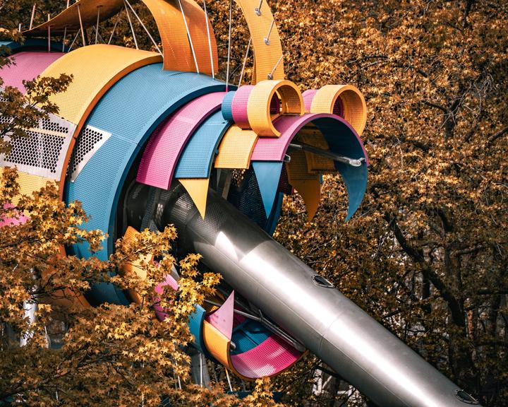 A child playing field structure that look like a colored monster with a metal tube that go out from it's mouth.