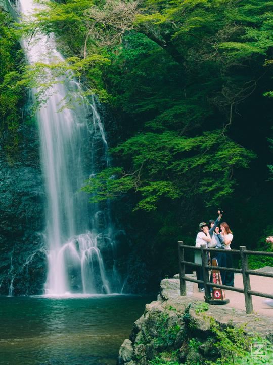 Tourists taking pictures of themselves in front of a beautiful waterfall 