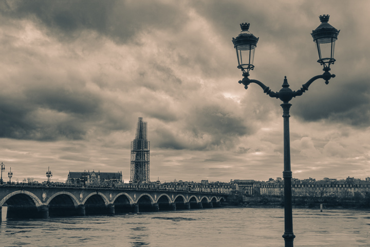 A stone bridge called Pont de Pierre crossing the Garonne in Bordeaux. You can see a twin public light on the right. On the background, you can see a tower surrounded by scaffolding for repair. 
https://www.flickr.com/photos/ztec/53412369313/
Albums: www