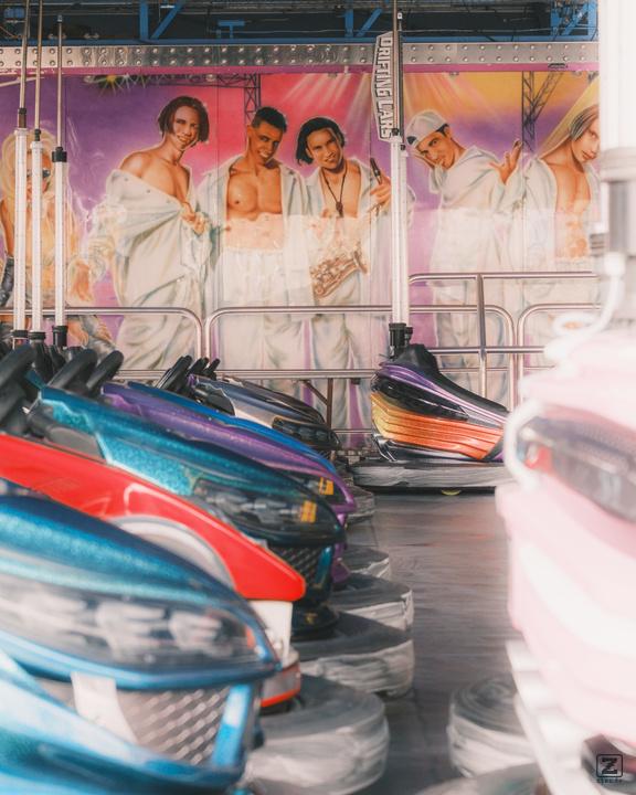 Bumpercars parked with a drawing on the wall of a generic boys-band.