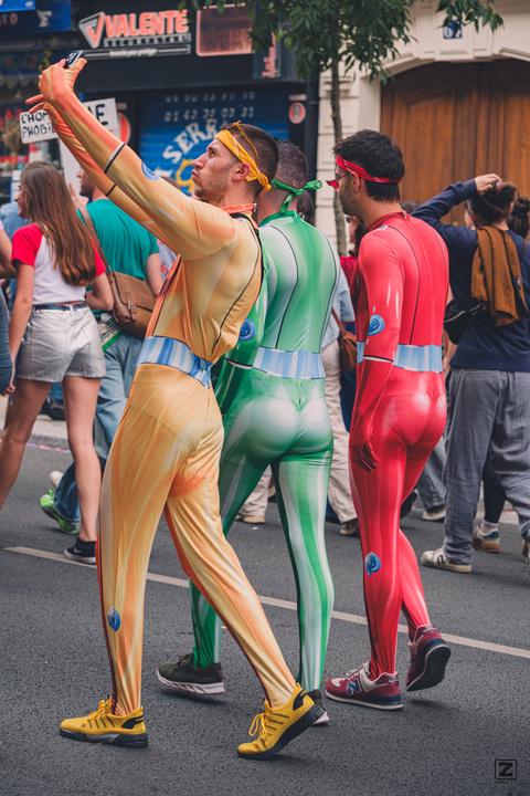 3 guy in full body costume of power-ranger like colors. One taking a selfie.