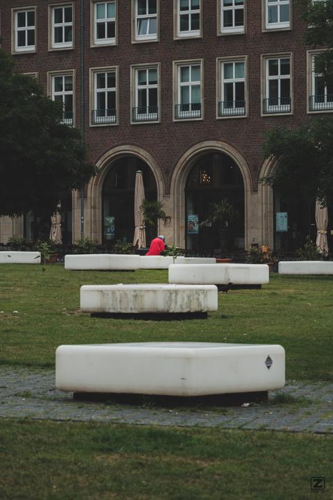 A person in red in the back with white and green foreground in a park.