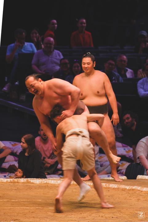 A sumo in battle with a child, losing to the power of the child.