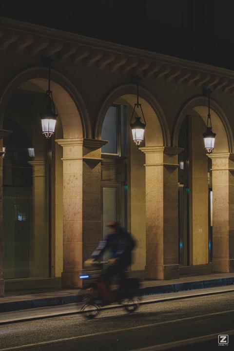 Paris arcades by night with a cyclist passing by