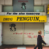 Someone walking in front of a closed store of DRUG PENGUIN