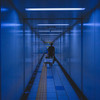 A man is pulling a chariot with a big case on it in the metro corridor. 