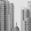 Sacré-coeur barely visible between two high rise building seen from afar. 