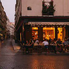 A bar in Paris (rue Montorgueil) with warm light coming from inside, reflecting on the pavement. 