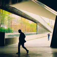 A silhouette of a man walking on the front, a photograph on the back, and a mix of light and shadow with sharp edges from the surrounding building