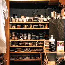 Back-end of a ceramic shop with shelf full of cup and ceramic pot. 
https://www.flickr.com/photos/ztec/53159188912/