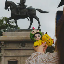 A tourist is taking picture of plushies in front of a monument.