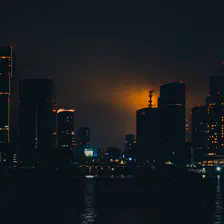 Tokyo bay at night with an orange glow coming from the Tokyo tower from behind skyscrapers