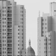 Sacré-coeur barely visible between two high rise building seen from afar. 
